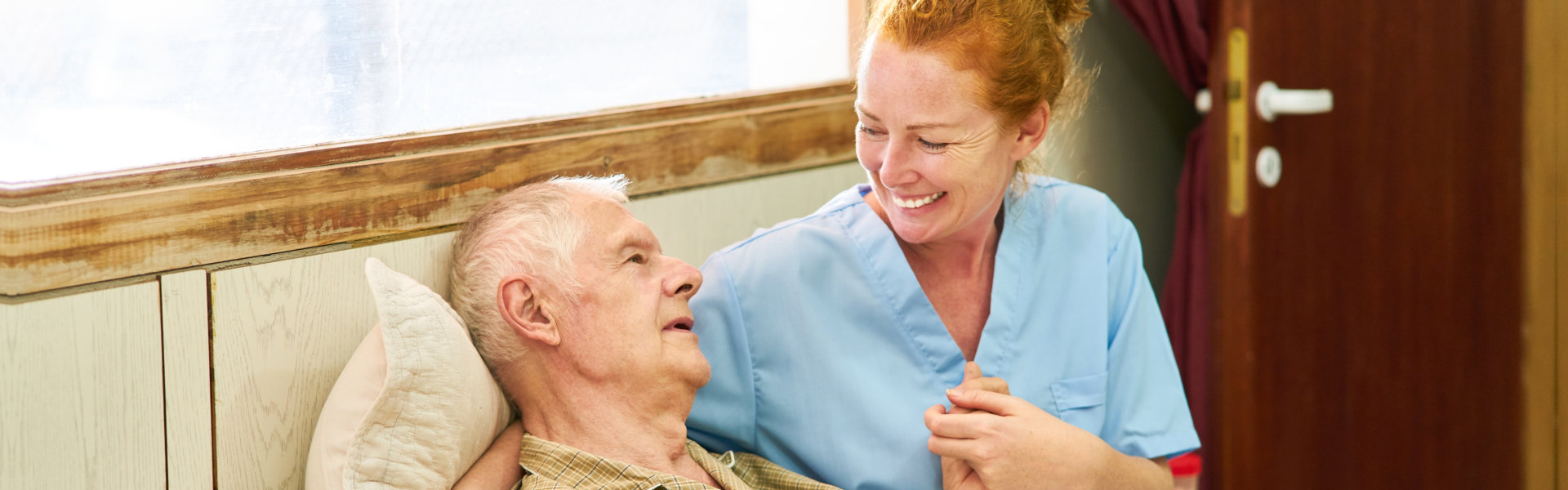 caregiver and elderly man lying in bed