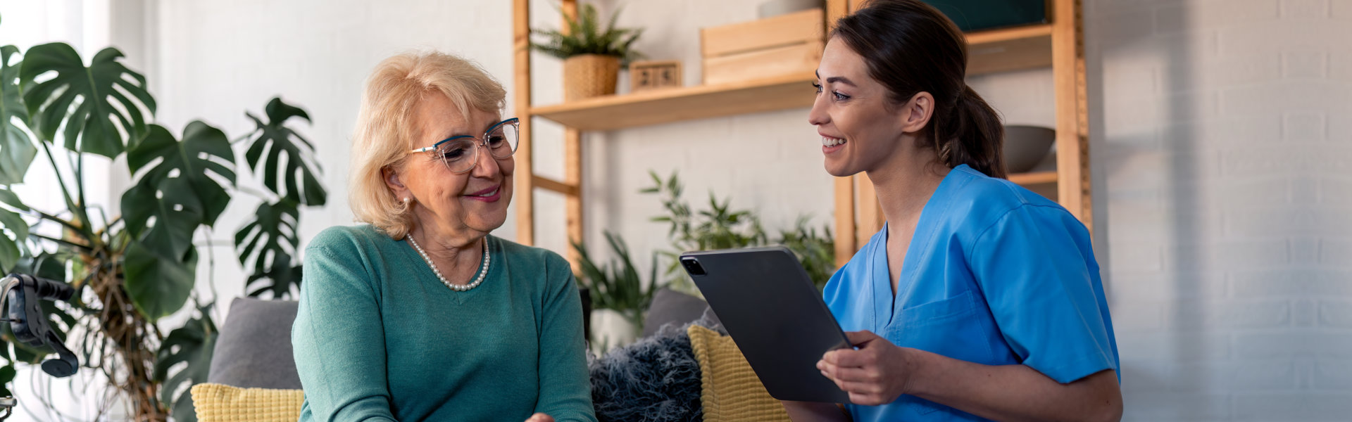 caregiver holding a tablet talking the senior woman